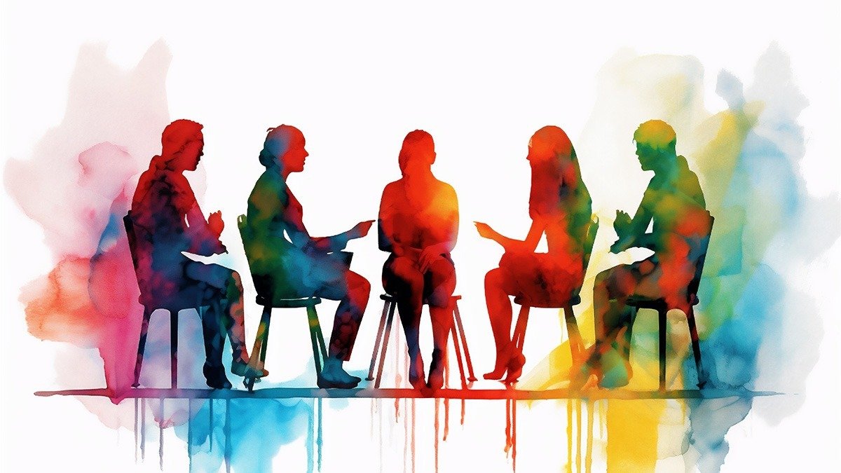 A support group meeting for recovering addicts with participants sitting in chairs and talking amongst each other.