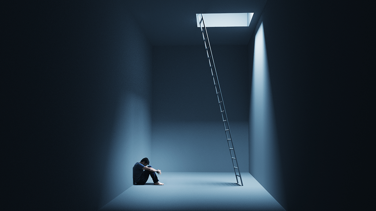 Man sitting reluctantly at the bottom of a ladder in the dark.